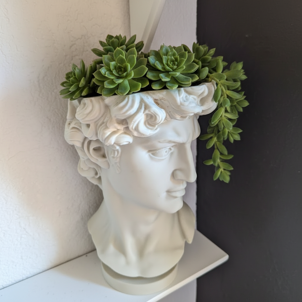 Decorative planter shaped like a classical bust with greenery on a shelf.
